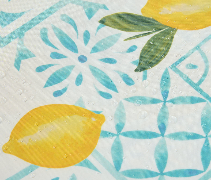 Gros plan d'un motif avec des citrons et des fleurs bleues, recouvert de gouttes d'eau.