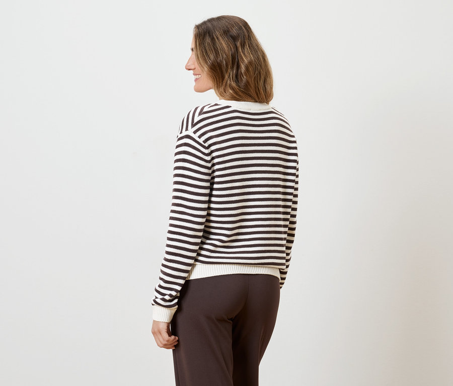 Femme vue de dos, portant un pantalon marron et un haut rayé à manches longues sur fond blanc.