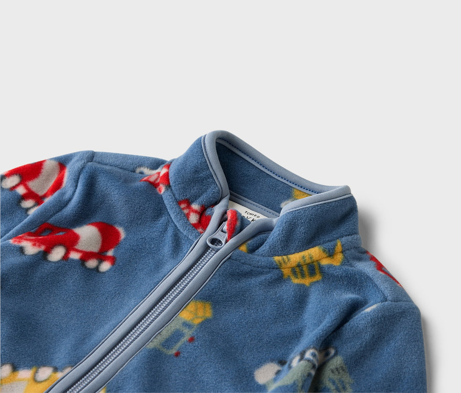 Gros plan sur une veste polaire bleue zippée avec des motifs de véhicules colorés.