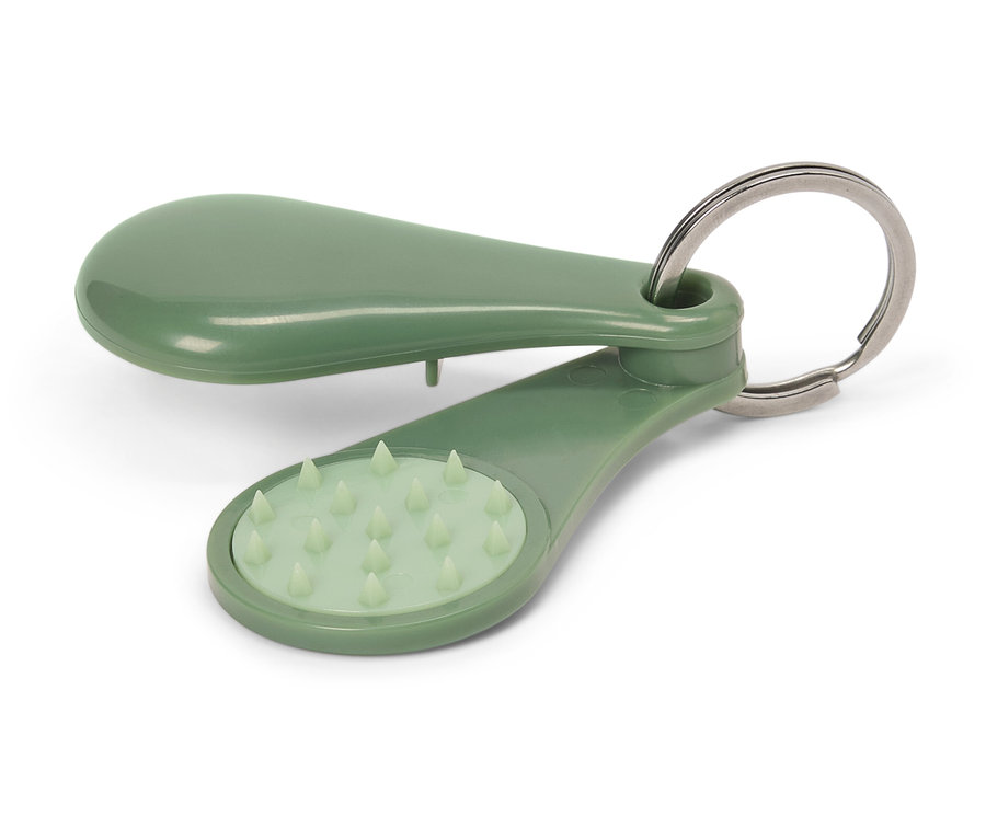 Un porte-clés de massage vert est posé sur un fond blanc.