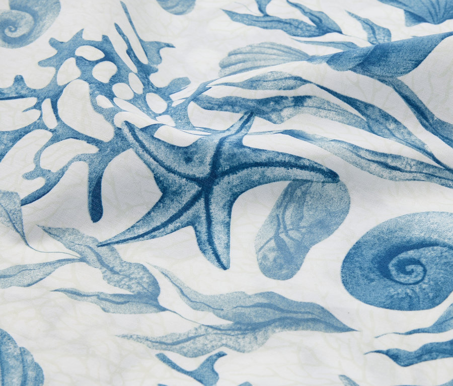 Gros plan d'un tissu avec un motif bleu d'étoiles de mer, de coquillages et d'algues.