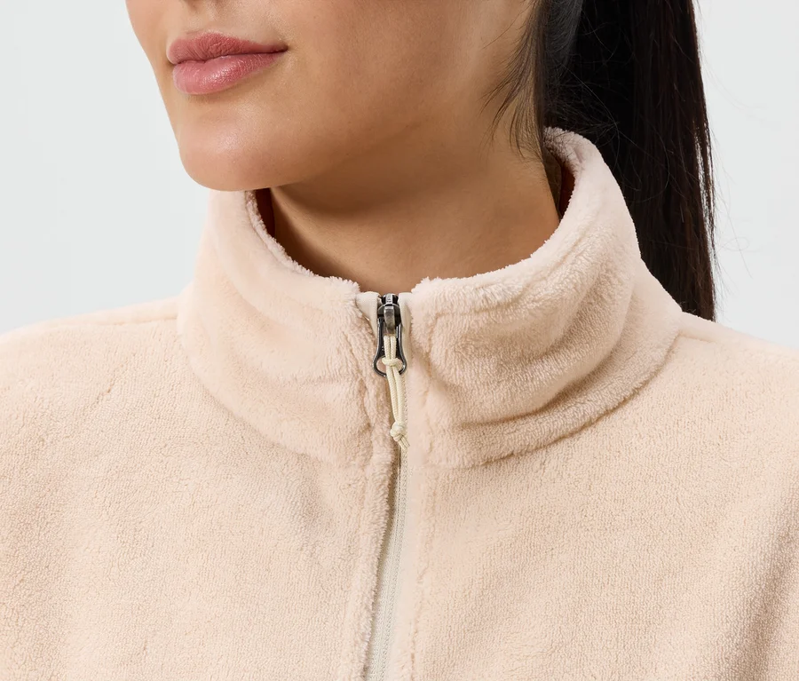 Gros plan d'une femme portant une veste en polaire rose clair zippée avec un col montant.