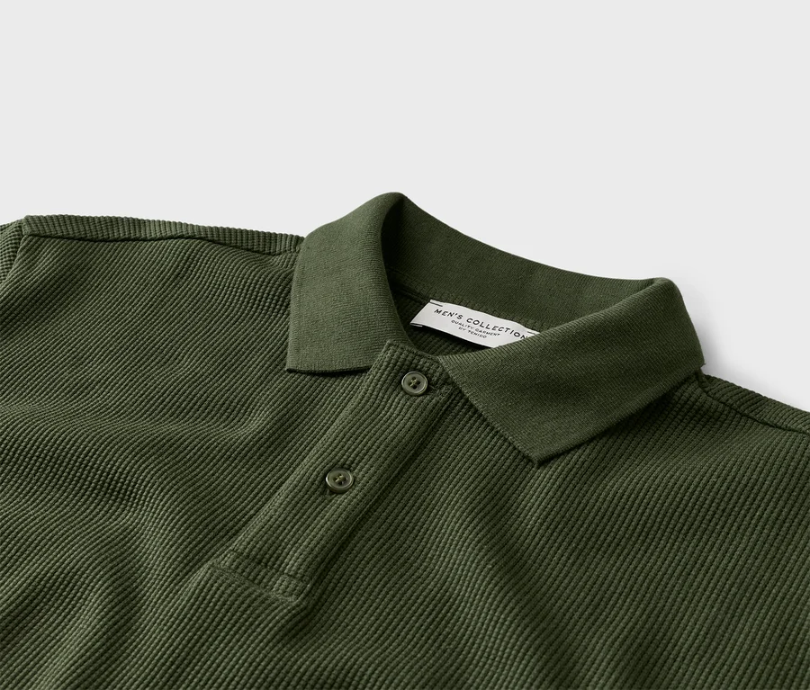 Gros plan d'un polo vert olive avec deux boutons et un col.