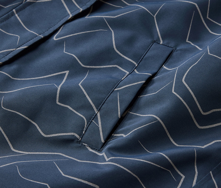 Gros plan sur une veste bleu marine avec un motif gris clair et une poche.