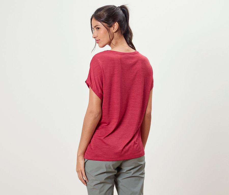 Une femme avec une queue de cheval porte un t-shirt rouge et un pantalon gris.