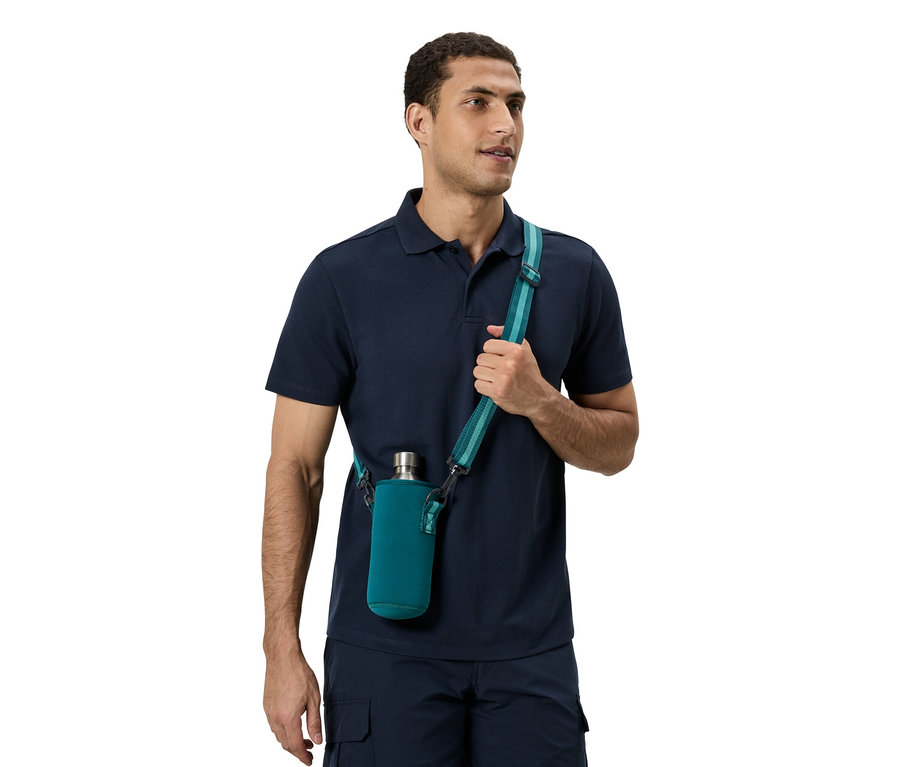 Un homme porte un polo bleu et un pantalon bleu. Il a une bouteille verte avec une bandoulière.