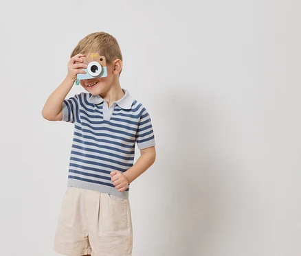 Un garçon tient un appareil photo jouet devant son œil.