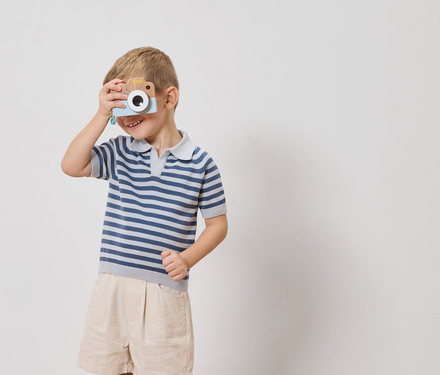 Un garçon tient un appareil photo jouet devant son œil.