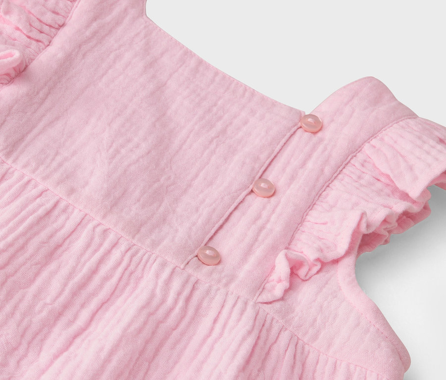 Gros plan sur une robe rose avec des volants et des boutons.