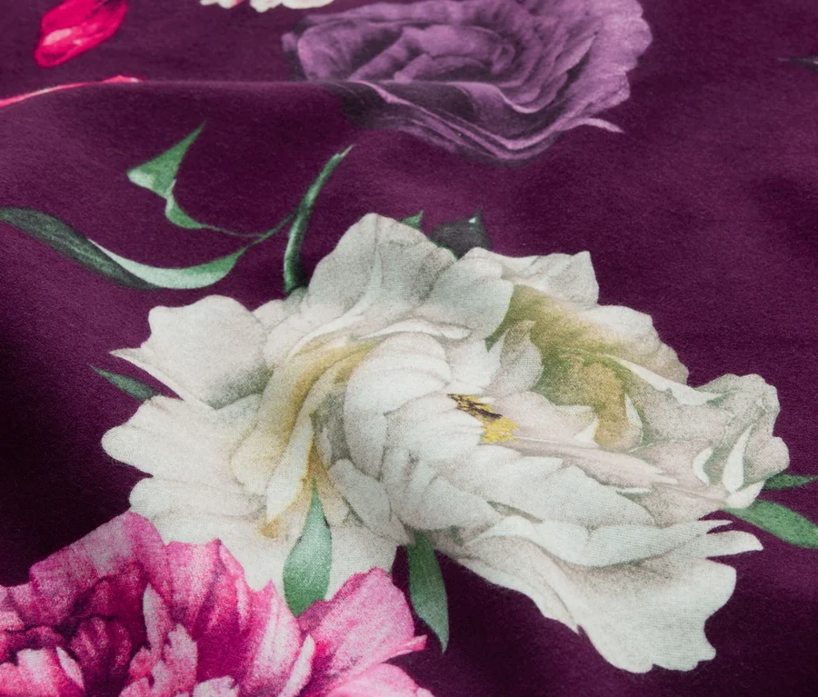 Tissu violet foncé avec un grand motif floral en blanc, violet et rose, avec des feuilles vertes.