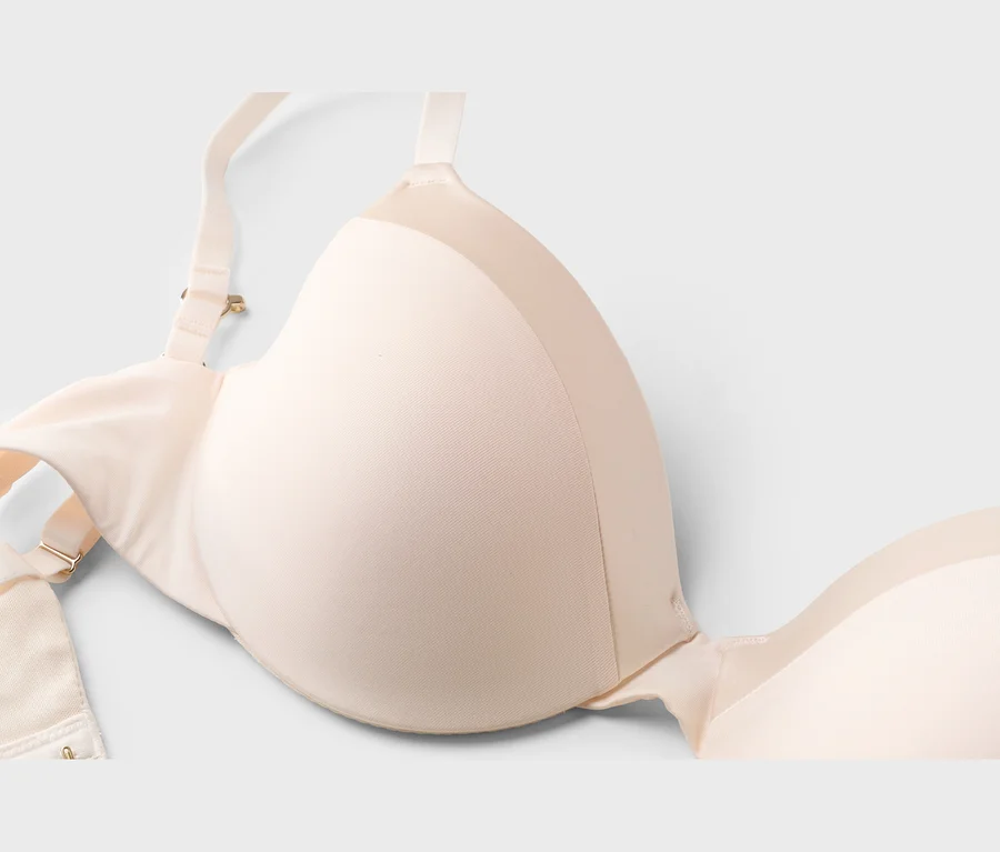 Gros plan d'un soutien-gorge beige clair avec des bretelles réglables et des bonnets moulés sur fond blanc.