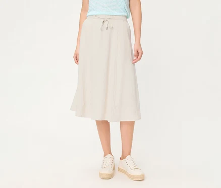 Personne portant une jupe en lin Olsen beige avec cordon de serrage et des baskets compensées blanches.