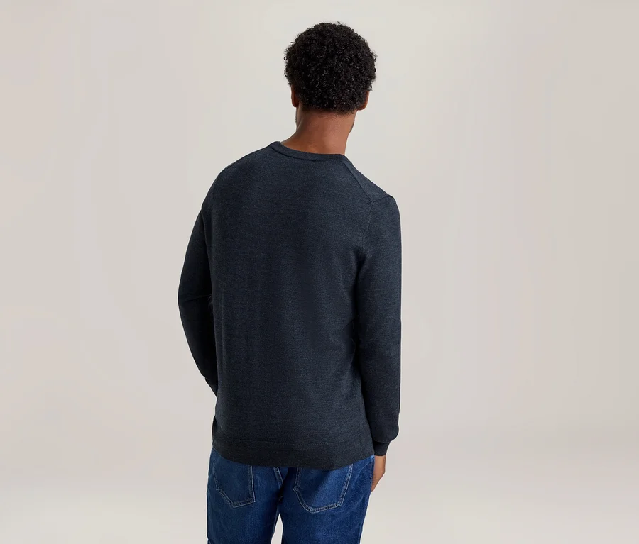 Personne de dos, portant un pull à manches longues bleu foncé et un jean bleu.