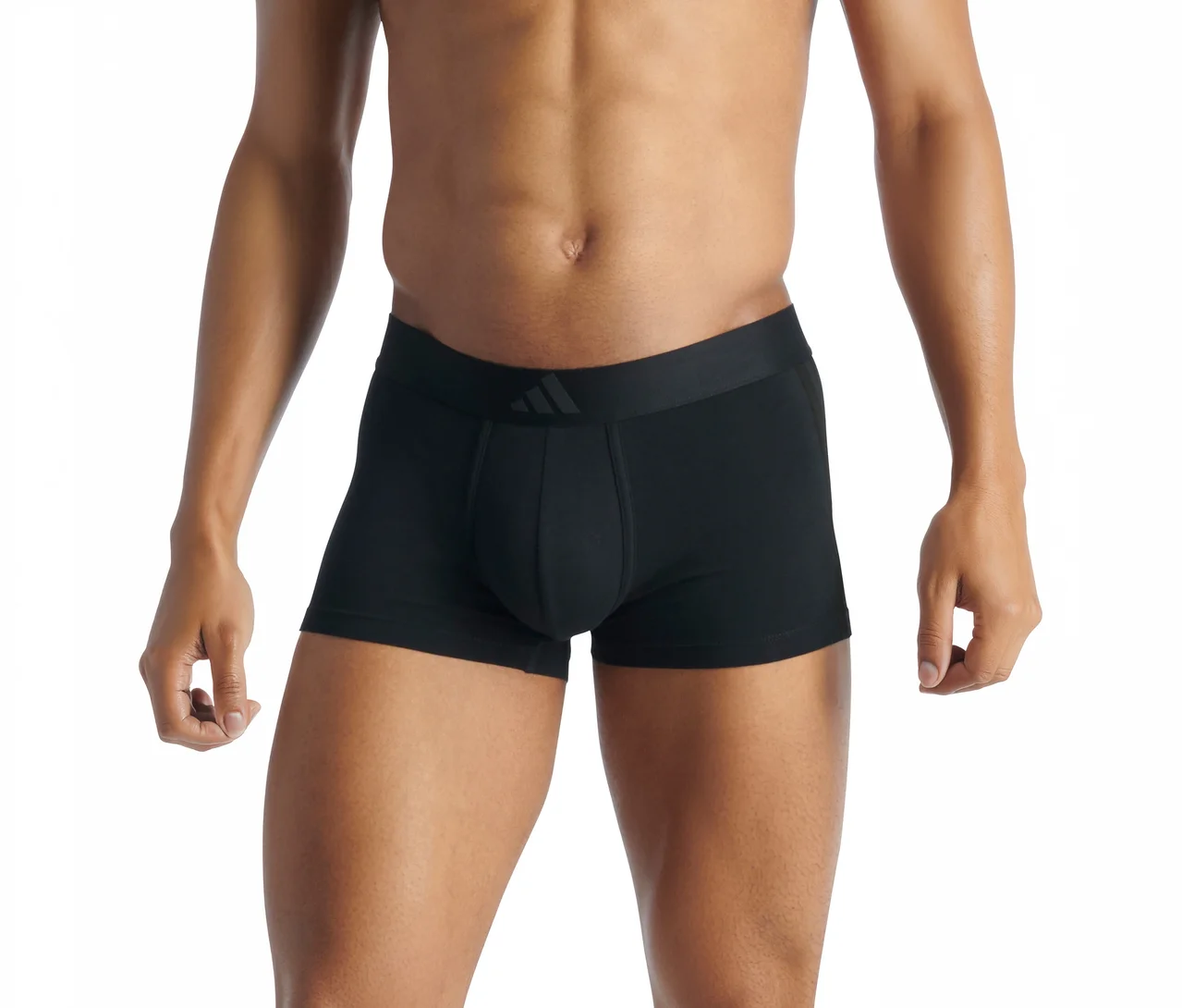 Homme portant un boxer noir avec un logo sombre sur la ceinture. Le torse, les bras et les cuisses sont visibles.