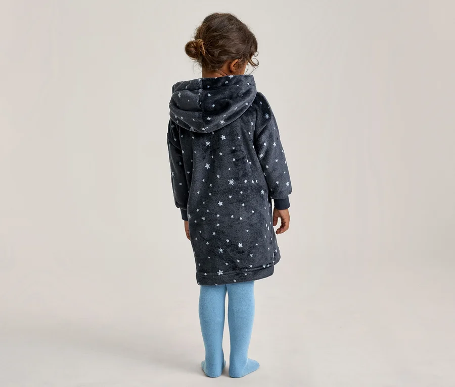 Enfant vu de dos, portant une robe à capuche bleu foncé avec des motifs d'étoiles blanches et des collants bleu clair.