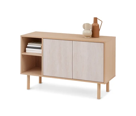 Un buffet en bois clair avec deux portes et des étagères ouvertes. Deux vases décoratifs sont posés sur le dessus, des livres sont rangés dans les étagères.