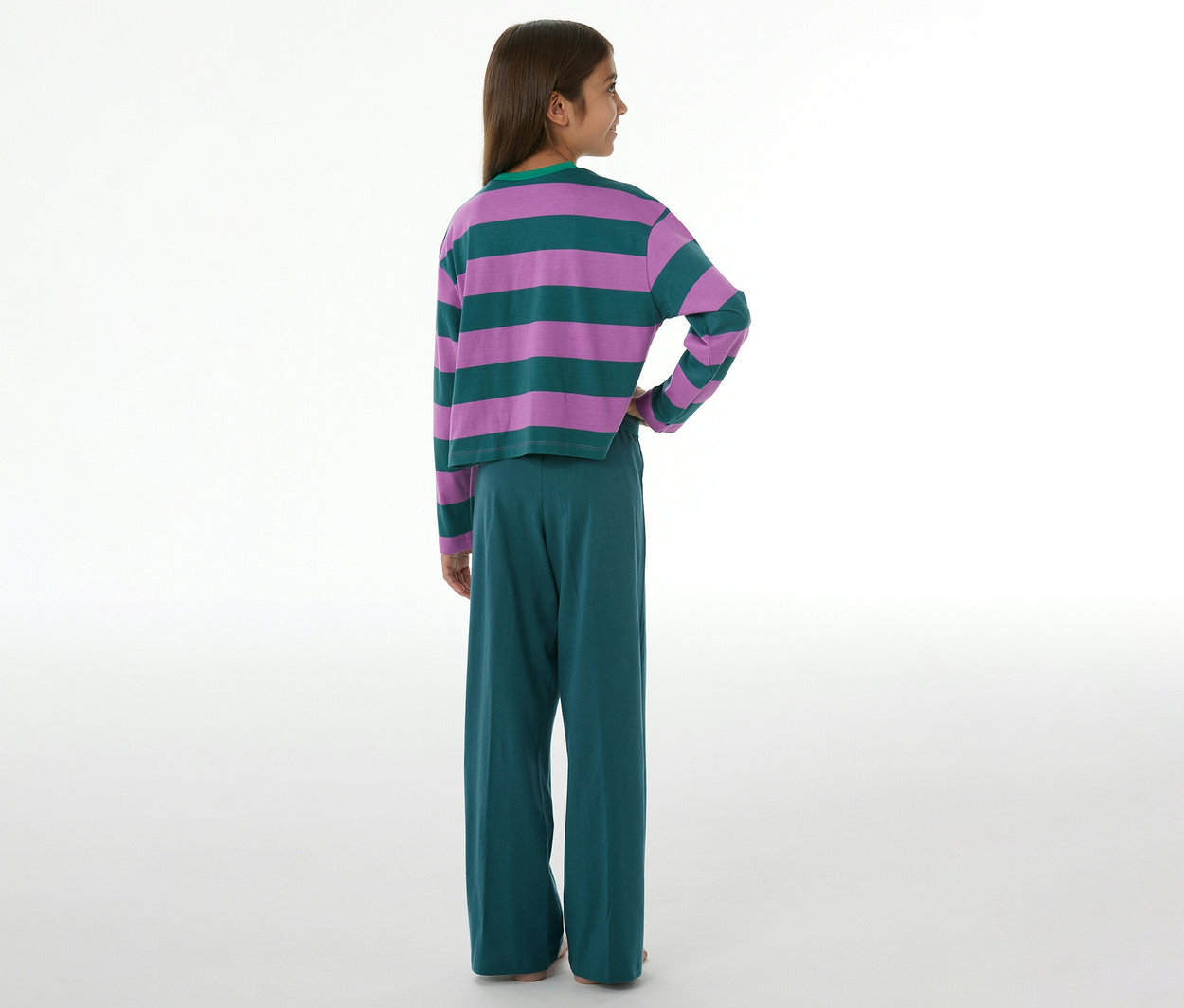 Enfant de dos, portant un pyjama pour enfant, composé d'un haut à manches longues rayé violet et vert et d'un pantalon vert à jambes larges.
