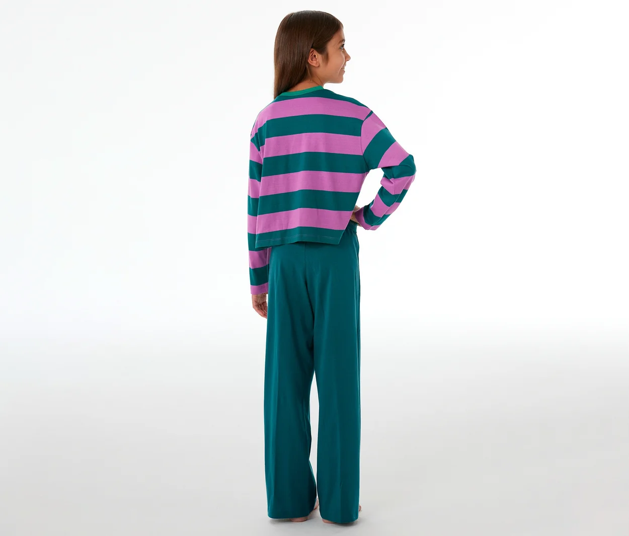 Fille vue de dos portant un pyjama enfant avec un haut rayé rose et vert et un pantalon vert.