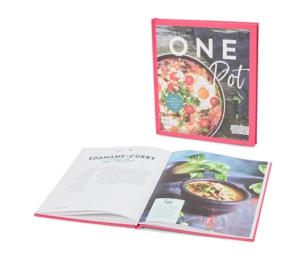 Un livre de cuisine intitulé « Simply One Pot » est ouvert sur une page contenant la recette du curry d'edamame au pak choi.