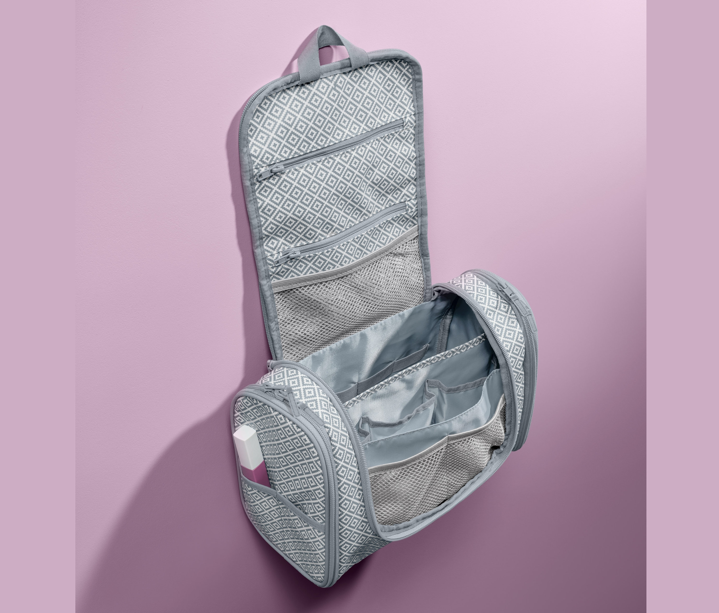 Trousse de toilette ouverte, grise, à motif géométrique.