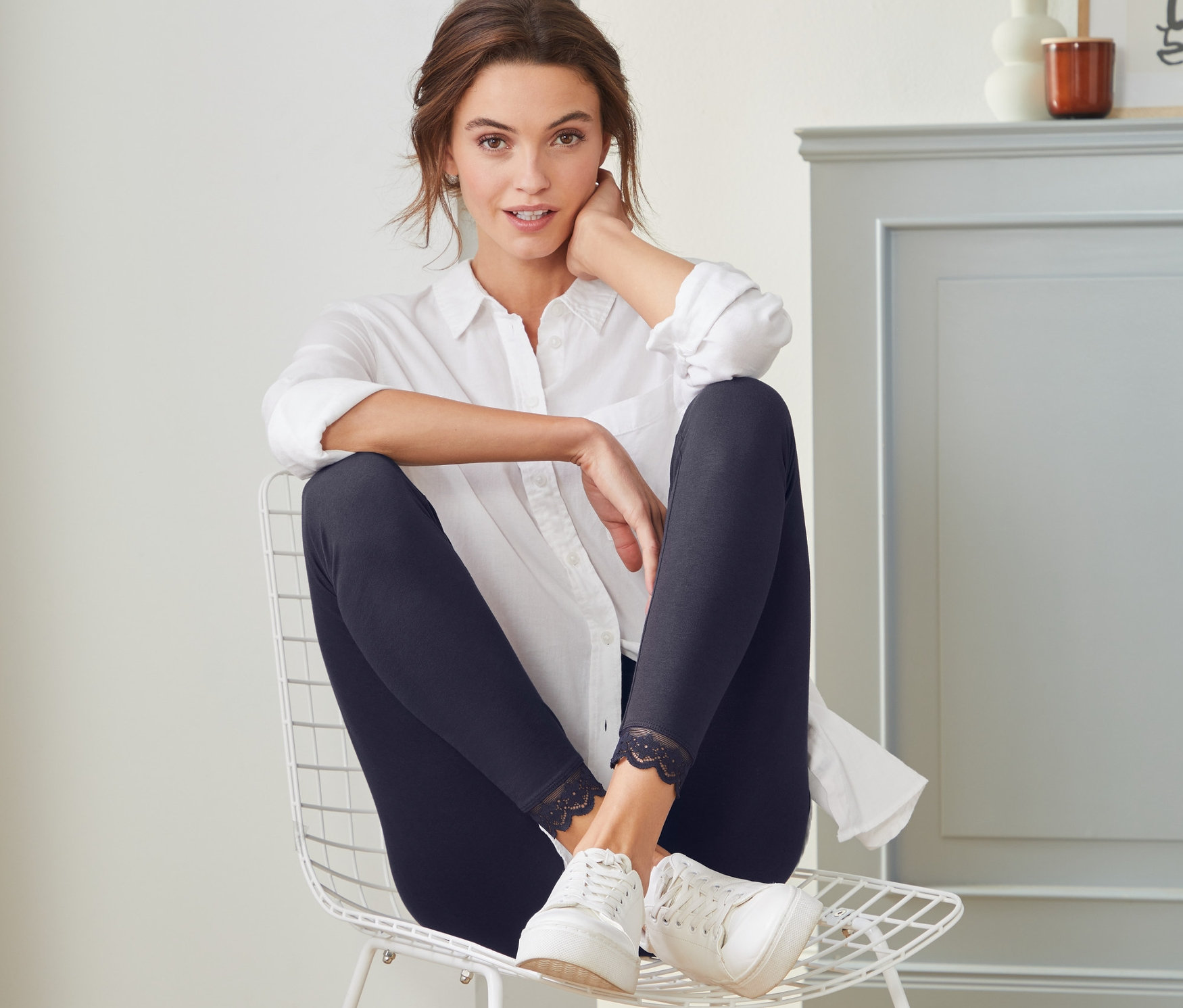 Une femme assise sur une chaise portant un legging avec bord en dentelle.