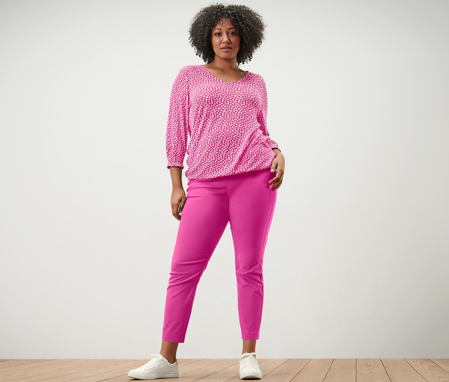 Femme posant en blouse imprimée rose vif et pantalon stretch rose vif.