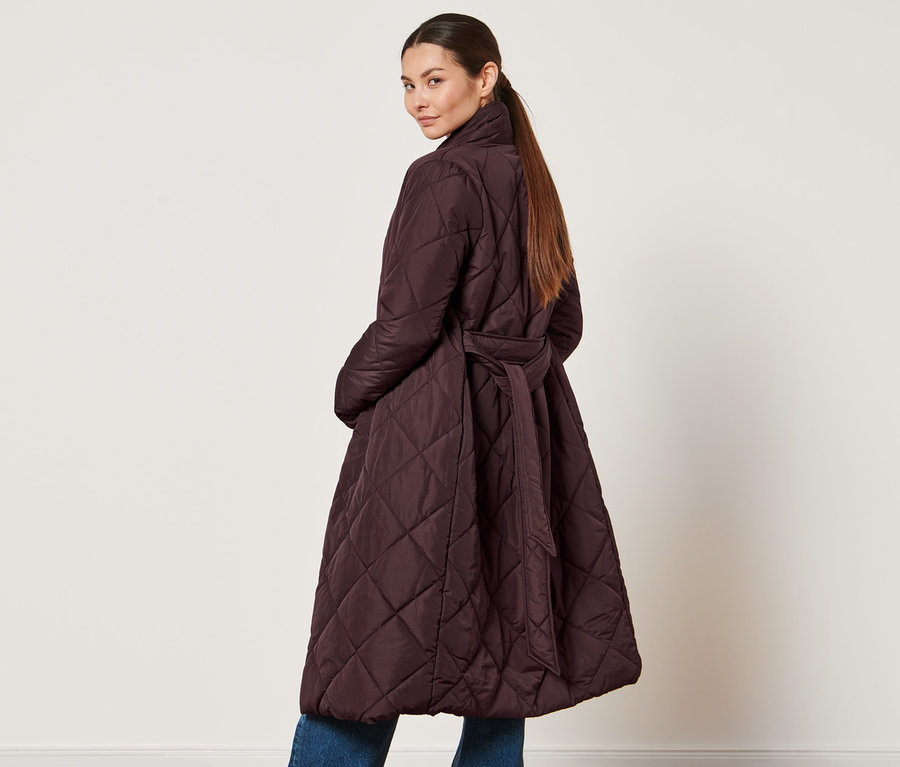 Femme regardant par-dessus son épaule portant un manteau matelassé.