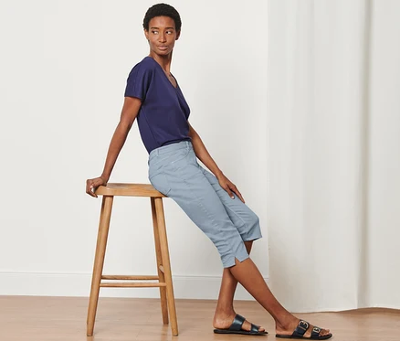 Une femme est assise sur un tabouret et porte un Denim Capri « Fit Mara ».