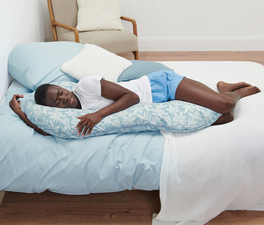 Femme dormant sur le côté sur un coussin XL pour dormir sur le côté avec une housse bleue à motif de feuilles.