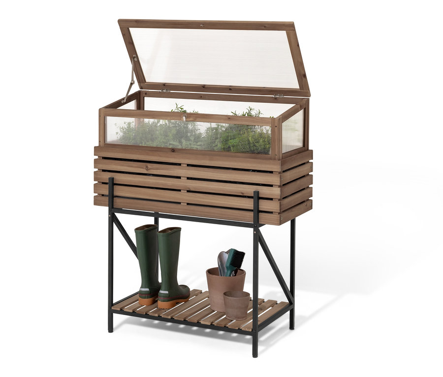 Jardinière surélevée « Elin » avec serre châssis, bottes en caoutchouc vertes et outils de jardinage sur l'étagère inférieure.