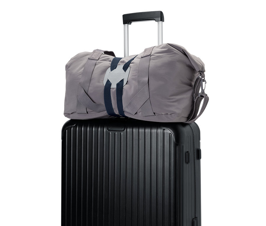 Un sac gris sur une valise noire avec extension de valise.