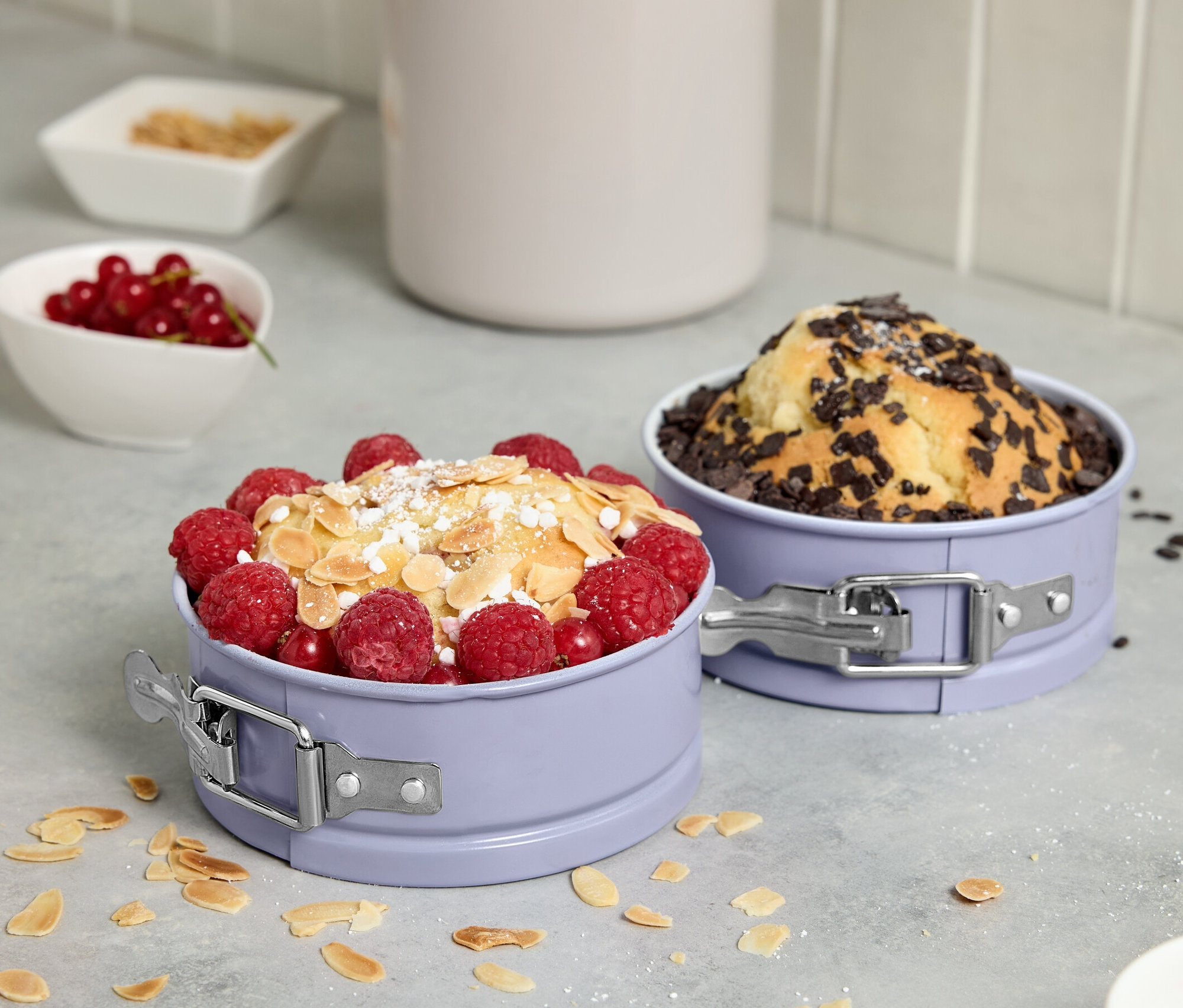 Deux mini-moules à charnière contenant des gâteaux garnis de fruits et de chocolat.