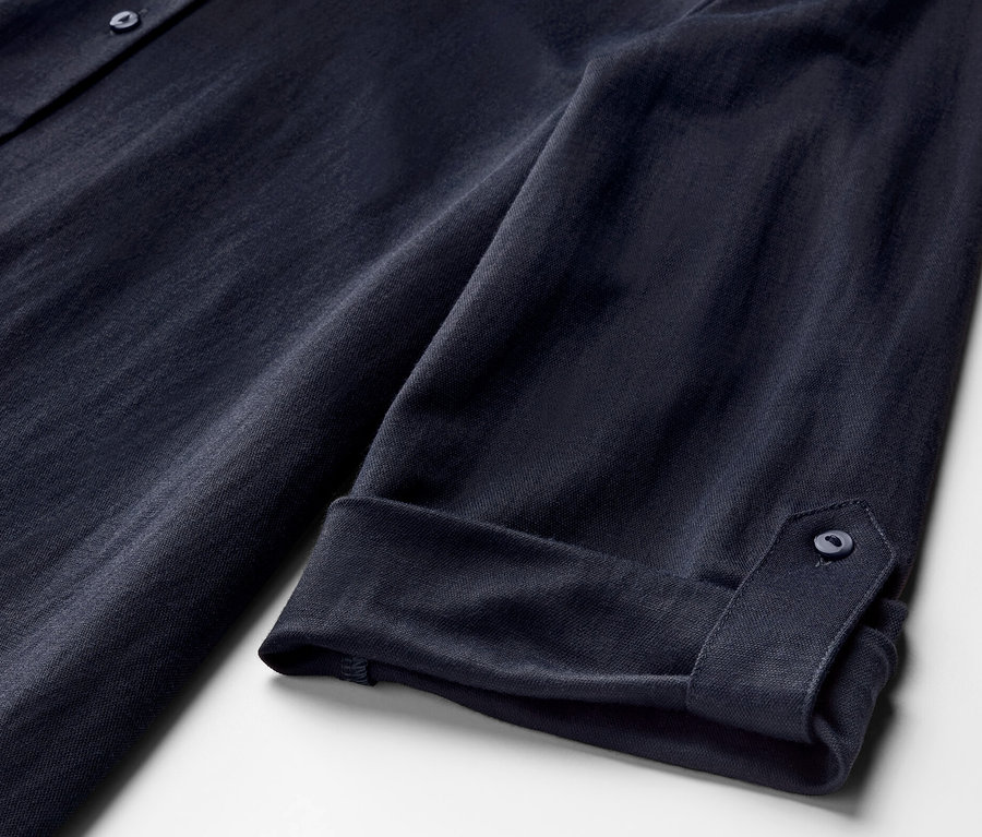 Détail d'un chemisier en jersey piqué bleu foncé avec des manches retroussées.