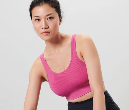 Une femme asiatique porte une brassière de sport sans coutures, un short de sport noir et un bandeau de sport violet.