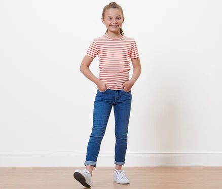 Une fille portant un t-shirt à rayures rouges et un jean, debout avec les mains dans les poches. 3 t-shirts enfant.