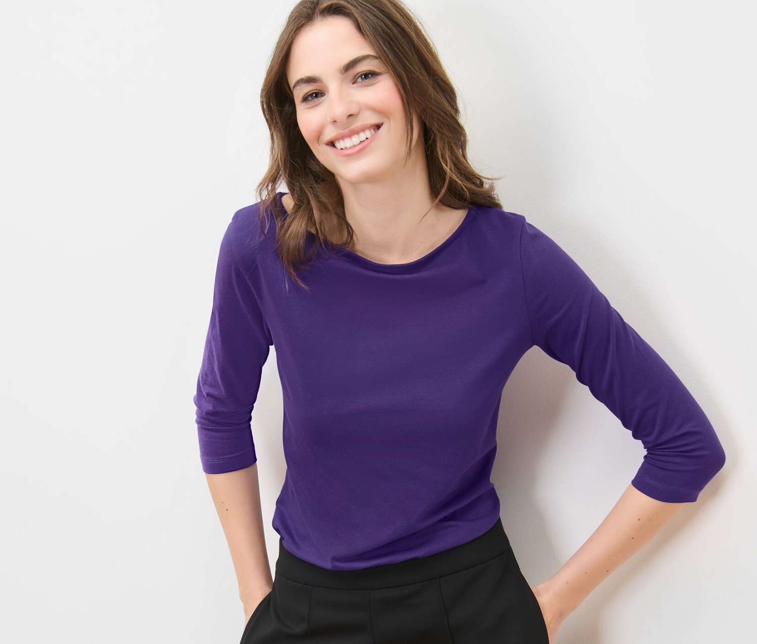 Femme posant dans un t-shirt violet à manches 3/4.