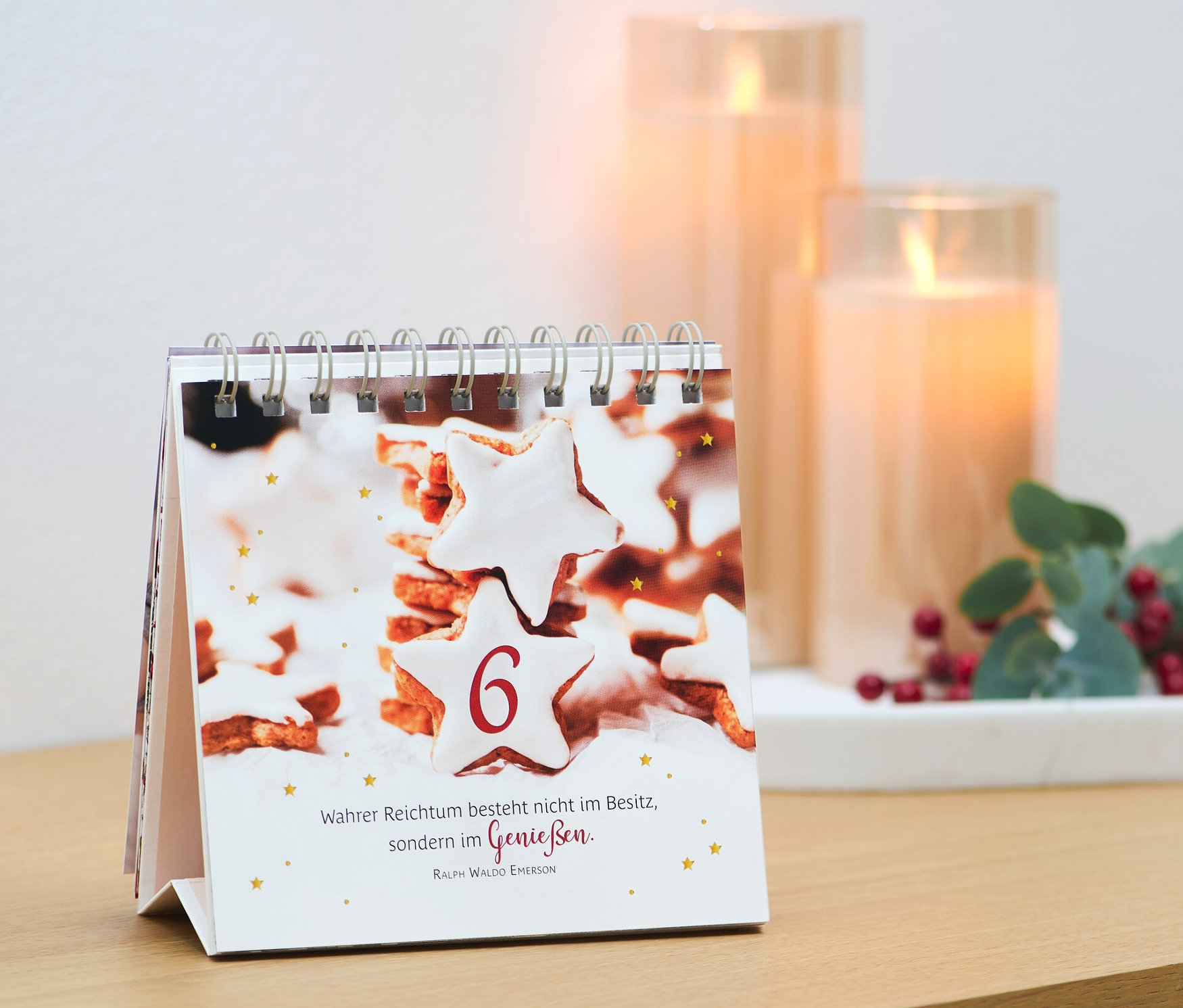 Un calendrier de table avec une image de biscuits et le chiffre 6, à côté de bougies et d'une décoration. Livre/présentoir : « Merveilles de l’Avent »