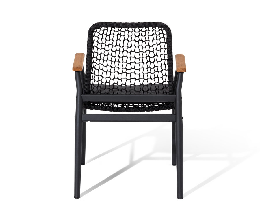 Une chaise de salle à manger avec des accoudoirs en teck et un tissage textile se dresse devant un fond blanc.