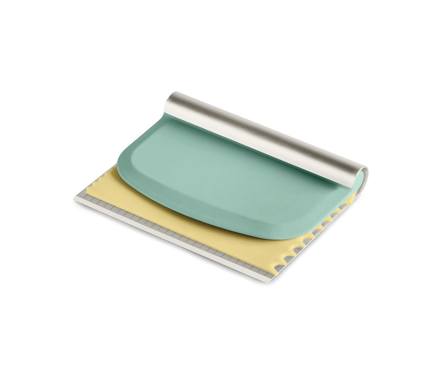 Un grattoir à pâte vert et jaune du kit d'accessoires professionnels de pâtisserie.