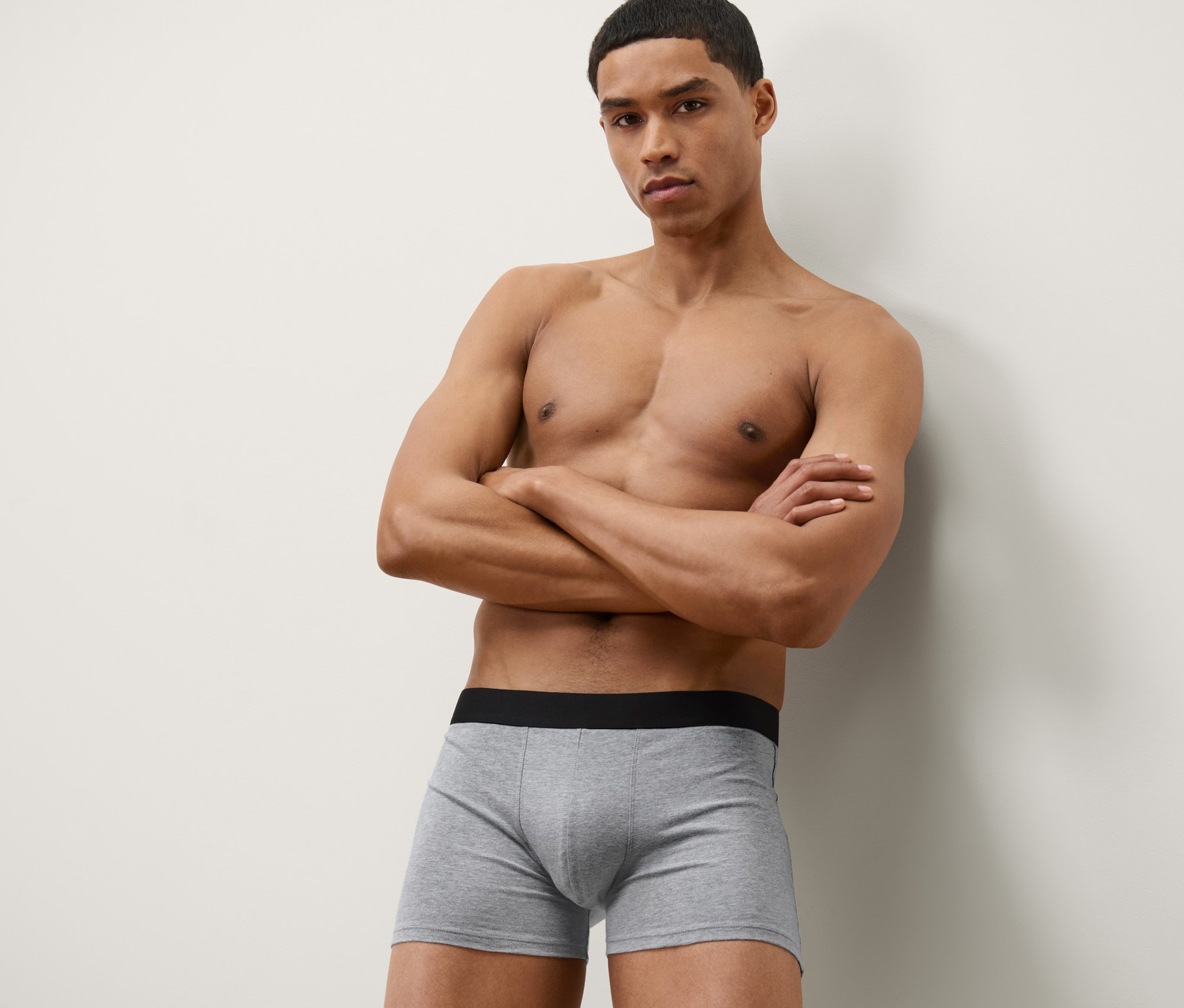 Un homme pose, les bras croisés, en portant un 4 Boxers gris.