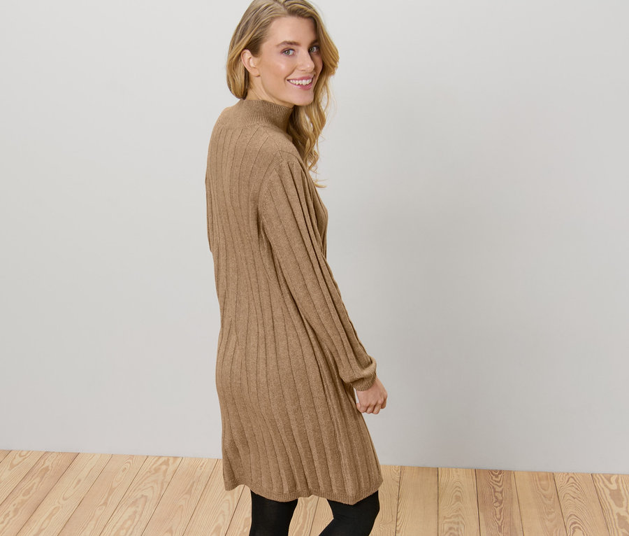 Une femme pose dans une robe en maille côtelée marron avec un col montant.