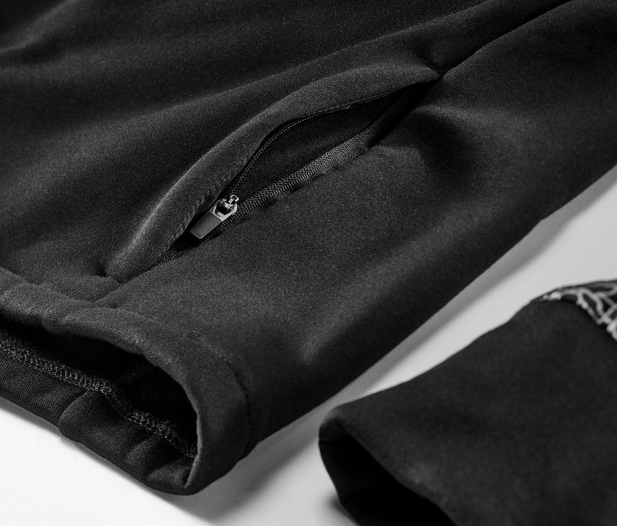 Gros plan sur une veste thermique noire avec une poche zippée et un bord de manche.