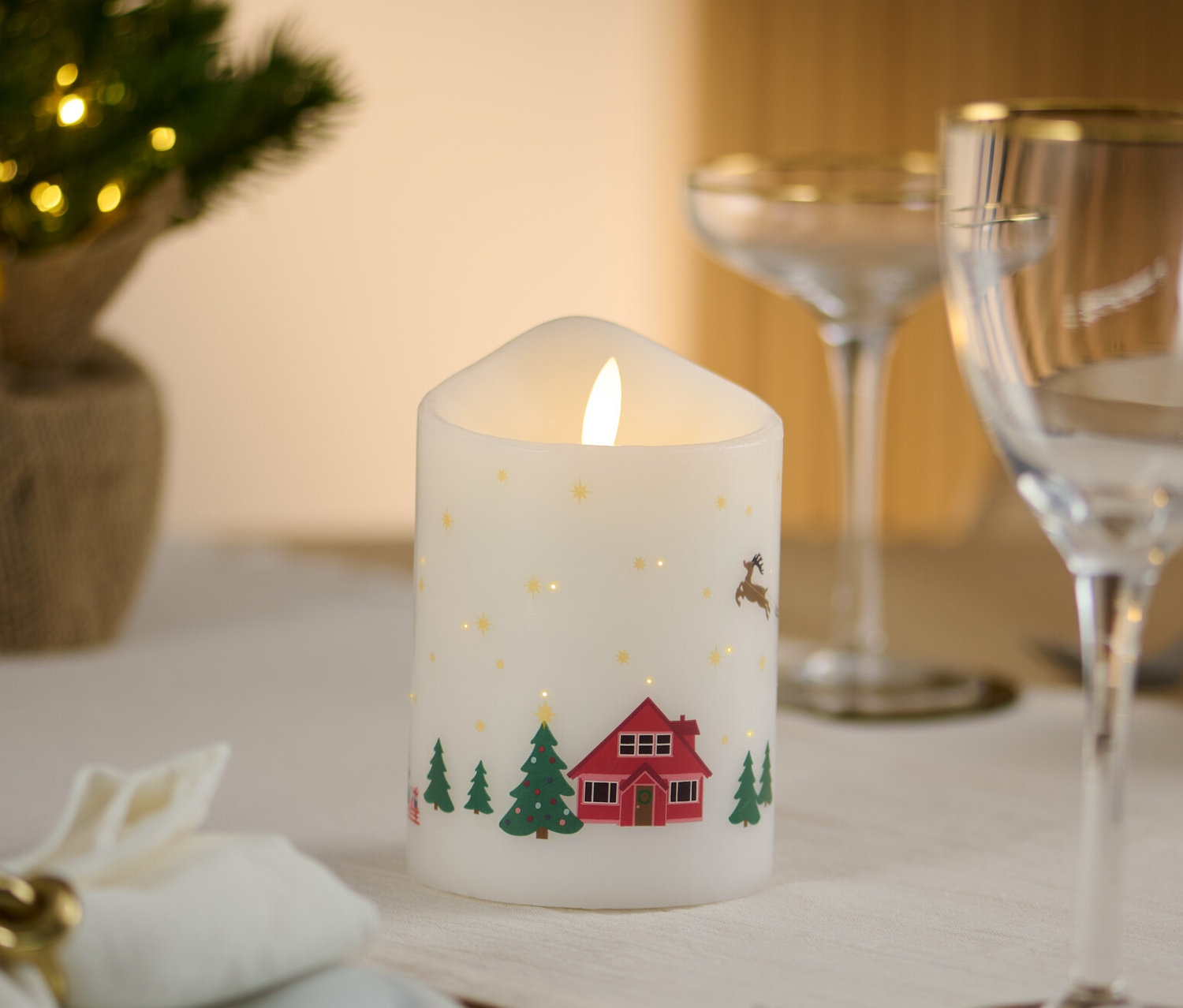 Sur une table dressée se trouve une bougie à LED en cire véritable avec un motif de Noël.
