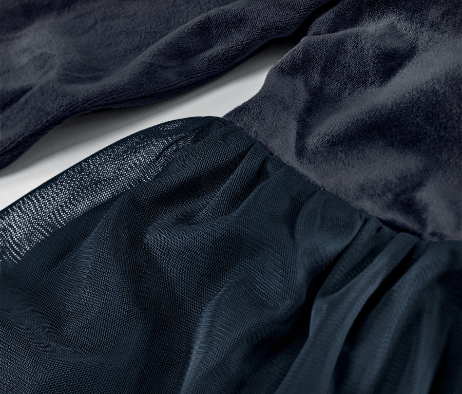 Gros plan sur une robe en tulle pour enfant, avec une jupe en tulle et un corsage en velours bleu foncé.