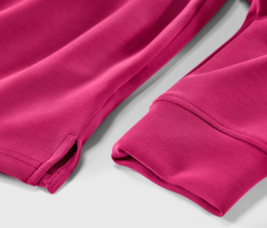 Vue détaillée d'un pull à capuche rose en mélange de modal, montrant l'ourlet de la manche et la fente.