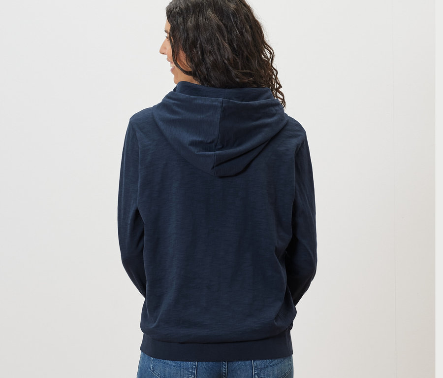 Vue arrière d'une femme aux cheveux foncés portant un sweat en jersey bleu marine.