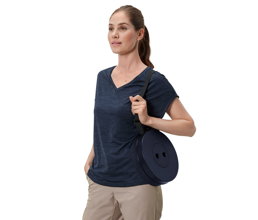 Femme portant un tabouret de camping télescopique sur l'épaule.