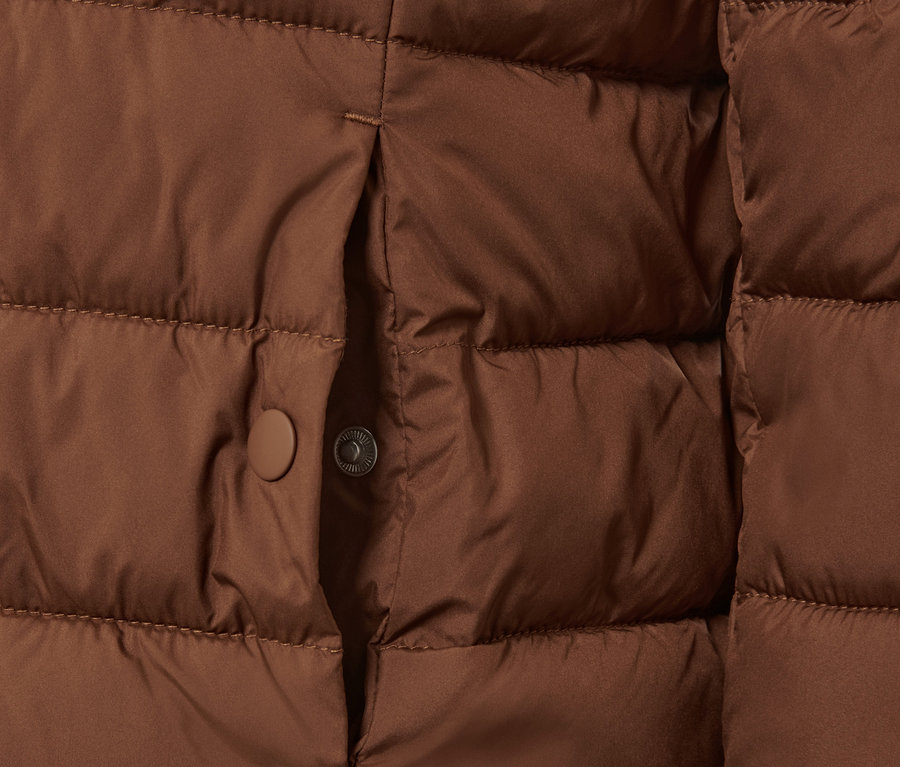Détail d'une veste matelassée à capuche couleur cognac.