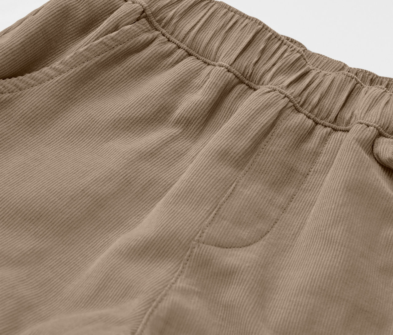 Gros plan sur un pantalon d’extérieur en velours côtelé marron pour enfants, montrant la taille élastique et une poche.