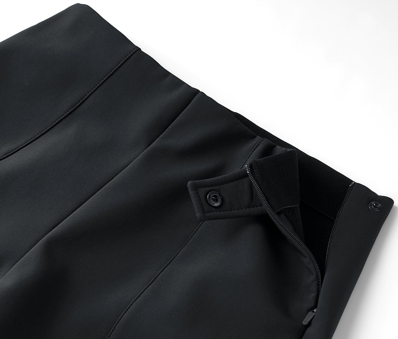 Détail d'une jupe noire avec fermeture éclair et boutons.